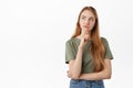 Thoughtful young woman making serious decision, looking up while pondering choices, frowning while thinking, standing in Royalty Free Stock Photo