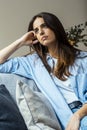 Thoughtful young woman with sad expression sitting on sofa at home looking outside and thinking bad problems on life. Lonely Royalty Free Stock Photo