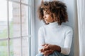 Thoughtful young woman sitting on modern white windowsill