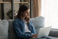 Thoughtful young woman sitting on sofa with computer on laps. Royalty Free Stock Photo