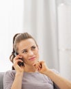 Thoughtful young woman sitting on sofa and talking cell phone Royalty Free Stock Photo