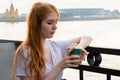 Pensive young woman holding paper cup with coffee while standing near river Royalty Free Stock Photo