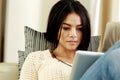 Thoughtful young woman using tablet computer at home