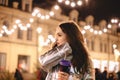 Thoughtful young woman walking in city street during Christmas holidays