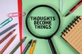 Thoughts become things. Text and magnifying glass on a green paper background