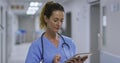 Thougtful caucasian female health worker using digital tablet in the corridor at hospital