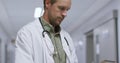 Thougtful caucasian male doctor using digital tablet in the corridor at hospital