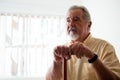 Thougtful senior man looking away while holding walking cane