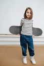 Thougthful little girl posing with skateboard for a photo, fake tired smile