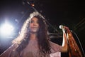 Thougthful young female singer holding mic at nightclub