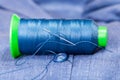 Thread bobbin with needle, button on blue jacket