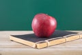 A thread-bound book and a red apple on the book in front of the blackboard Royalty Free Stock Photo