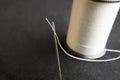 Thread in needle eye with spool on black Royalty Free Stock Photo