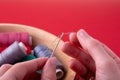 Thread into needle process woman hands on red background Royalty Free Stock Photo