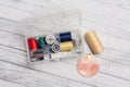 thread needles sewing supplies in a plastic box on a wooden background