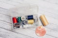 thread needles sewing supplies in a plastic box on a wooden background