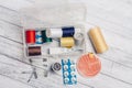 thread needles sewing supplies in a plastic box on a wooden background