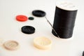 Threaded needle, black thread spool and buttons Royalty Free Stock Photo