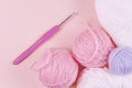Threads for knitting in white, gray and pink colors on a pink background. Crochet hook and thread