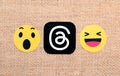 Threads mobile app icon with Wow and Haha Facebook reactions on sackcloth textile background close-up. Unexpected start