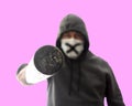 Isolated on pink hooligan in mask and hoodie pokes in face with baseball bat