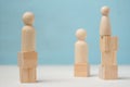 Three abstract wooden figures of people stand on different levels