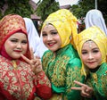 Three Acehnese girls, dressed in traditional attire, smiling radiantly, embodying the cultural charm of Aceh.