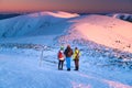 Three active hikers watching the sunrise scenery in winter landscape. Hiking together, teamwork in mountains, concept photo. Royalty Free Stock Photo