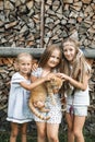 Three adorable happy little girls and a red cat outdoors. Kids and pets. Little girls hugging cute red cat standing near Royalty Free Stock Photo