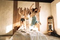 Three adorable teenage girls of different races are jumping on the bed. Attractive multiethnic girlfriends are having a party Royalty Free Stock Photo