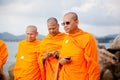 Three adult monk tourist wearing glasses and a orange dress with a camera and a phone in Thailand on Koh Samui