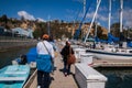 Three adults walking away on a dock past boats