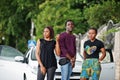 Three african american friends stay near car.