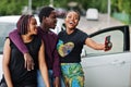 Three african american friends stay near car.