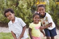 Three African American kids in a garden looking to camera