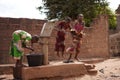 Three African Girls Showing Off Teamwork Skills Collecting Water At a Borhole Hand Pump Royalty Free Stock Photo