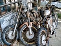 Old, rusty motorcycles stored outside a worn-down garage with peeling paint Royalty Free Stock Photo