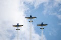 Three airplanes in the sky within clouds performing acrobatics during an air show