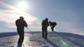 Three Alpenists climb rope on snowy mountain. Tourists work together as team shaking heights overcoming difficulties