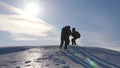 Three Alpenists climb rope on snowy mountain. Tourists work together as team shaking heights overcoming difficulties