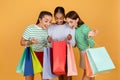 Three amazed multiracial girlfriends looking inside shopping bags Royalty Free Stock Photo