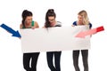 Three amazed women pointing arrows to a big blank board