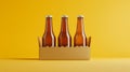 Three amber beer bottles in cardboard carrier on yellow background Royalty Free Stock Photo