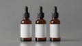 Three amber glass dropper bottles with blank white labels arranged in a row on a grey background Royalty Free Stock Photo