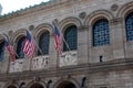 Three American flags hanging above the entrance doors of the Central Boston Public Library in Boston