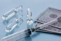 Three ampullas, expendable syringe for vaccination and paper money. The concept of insurance medicine, high cost of drugs