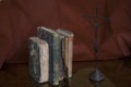 Three ancient stained books by a modern abstract metallic statue of Jesus Christ on the cross