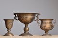 Three antique bronze vases on a wooden table on a light gray background Royalty Free Stock Photo