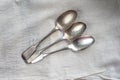 Three antique silver spoons on a white cloth Royalty Free Stock Photo
