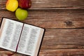 Three apples in different colors with Holy Bible Book isolated on wooden table Royalty Free Stock Photo